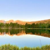 Mountain lake reflecting trees and blue sky