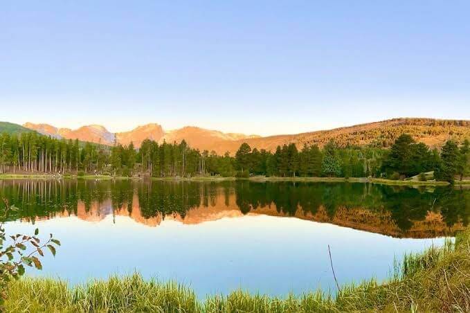 Mountain lake reflecting trees and blue sky