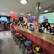 Sports bar interior with bartender and multiple screens