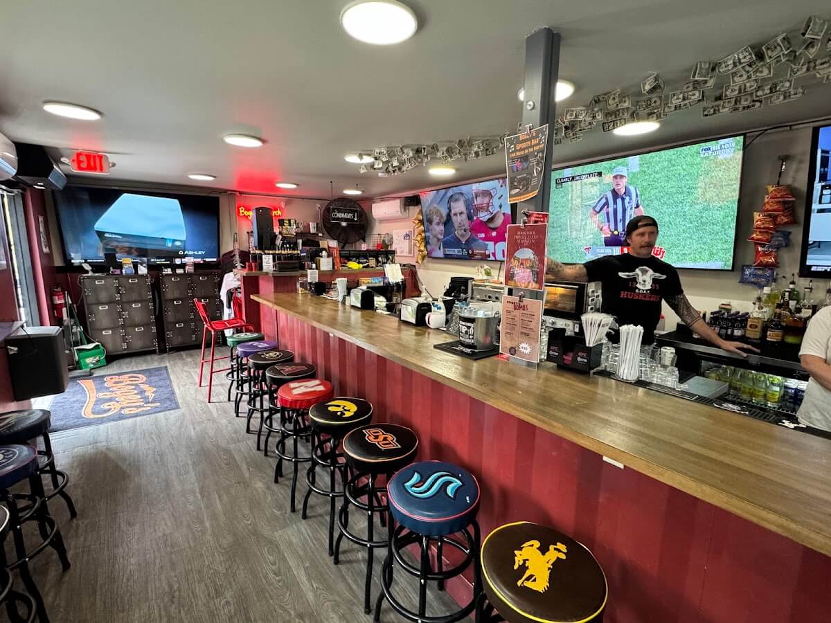 Sports bar interior with bartender and multiple screens