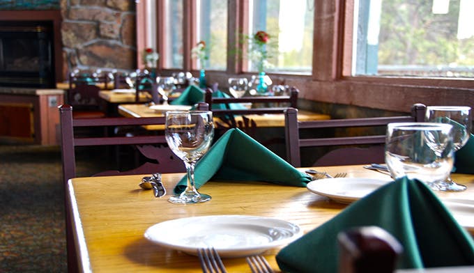 Restaurant tables set with green napkins and water glasses